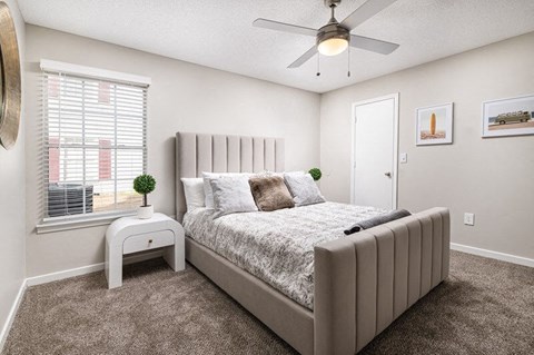 A bedroom with a large bed and a ceiling fan.