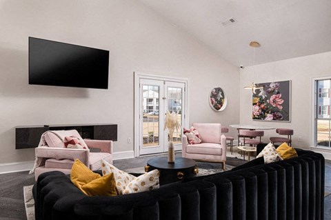 A living room with a black couch and a flat screen TV mounted on the wall.