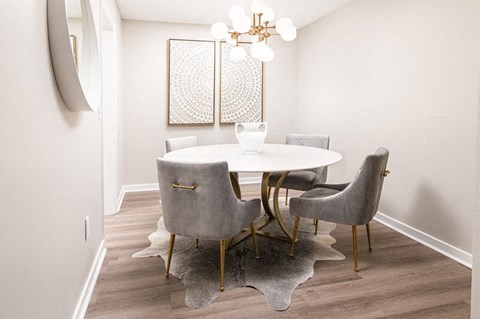 A dining room with a white table and grey chairs.