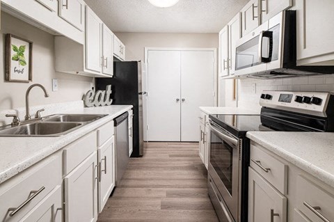 A kitchen with white cabinets and a black refrigerator.