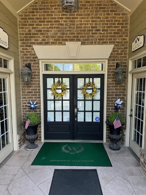 front door of a home with wreaths on the windows and a green rug