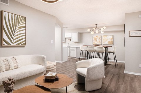 A living room with a white couch, a coffee table, and a dining area in the background.