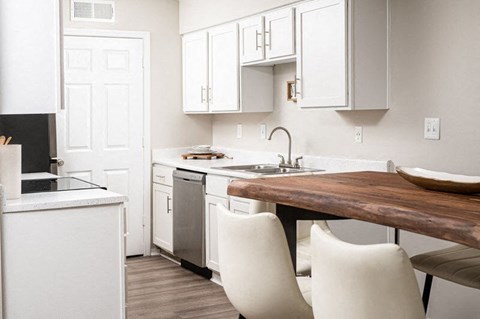 A kitchen with white cabinets and a wooden island.