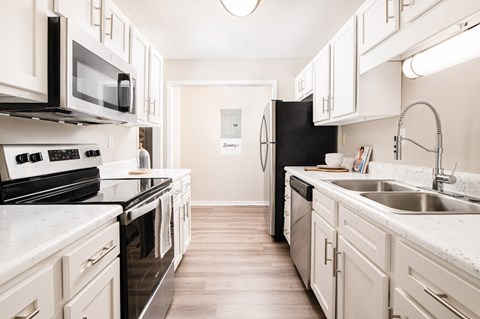 a kitchen with white cabinets and black appliances and a sink