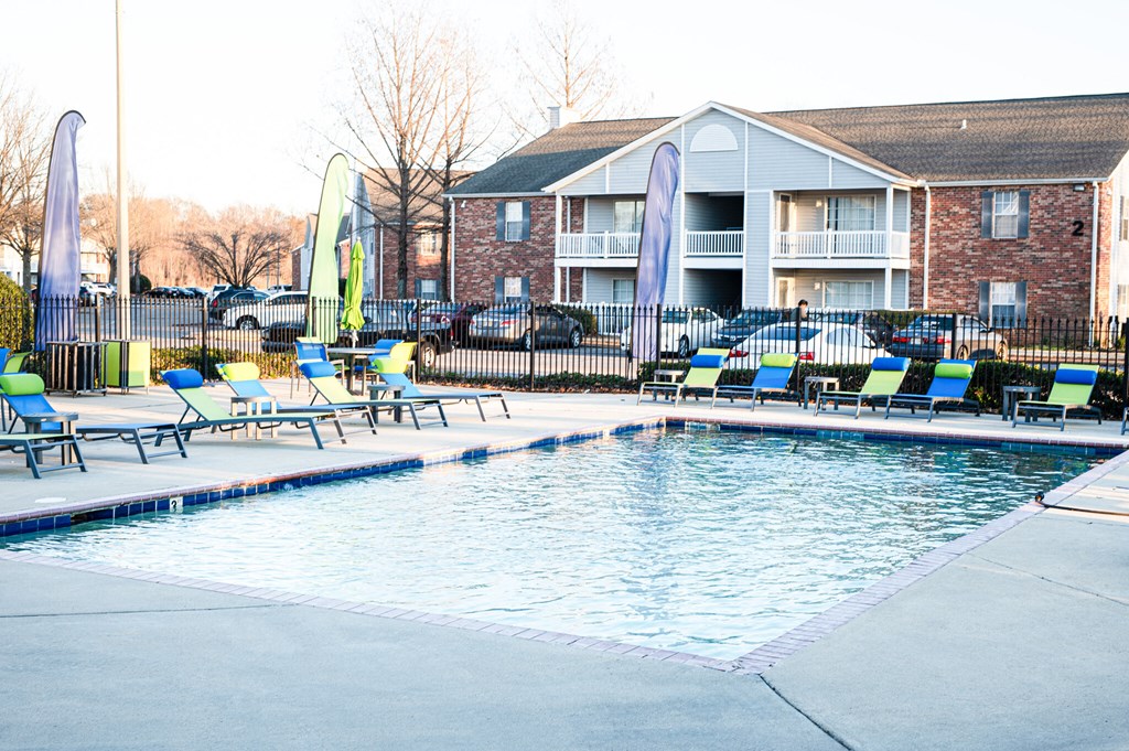 a swimming pool with chairs and a building in the background