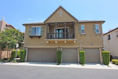 a yellow house with two garage doors and a balcony