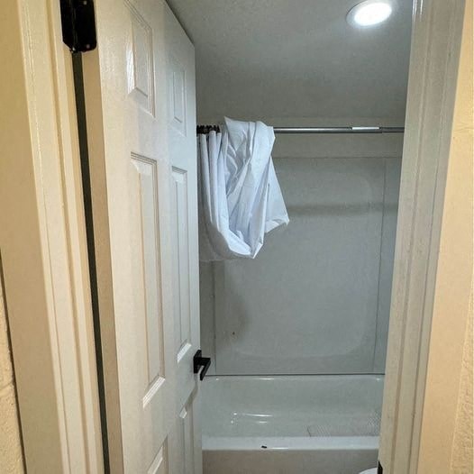 a bathroom with a white shower and a towel hanging from the door