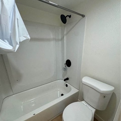 a white bathroom with a toilet and a bath tub