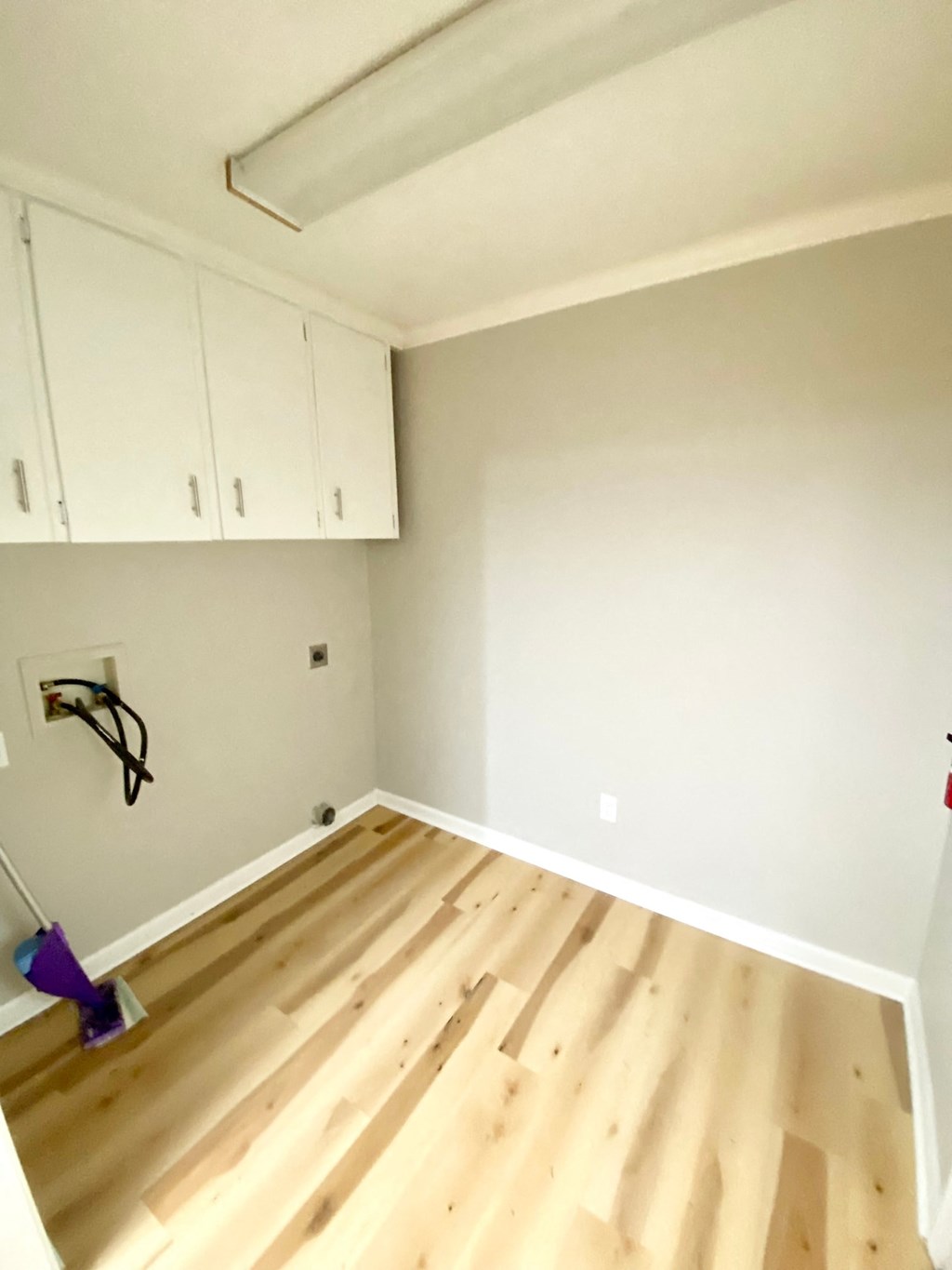 a room with wooden floors and white cabinets