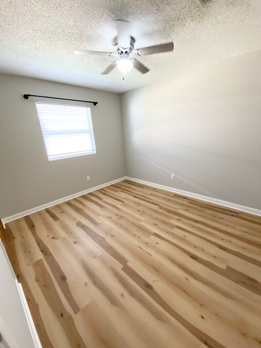 an empty room with wooden floors and a ceiling fan