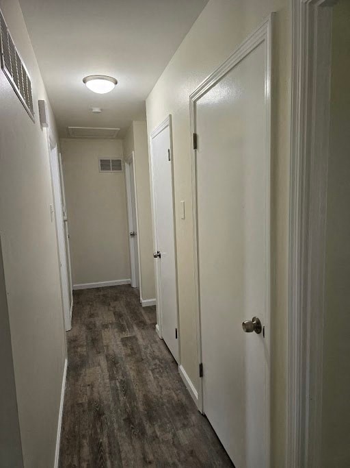 a hallway with white walls and wooden floors and a white door