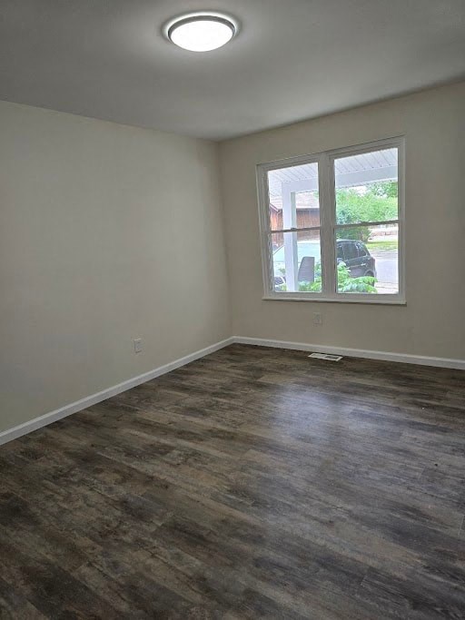 an empty living room with a window and wooden floors