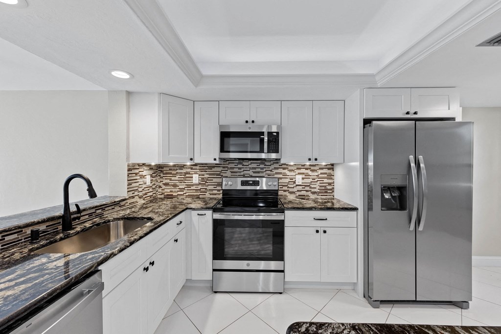 a kitchen with white cabinets and stainless steel appliances