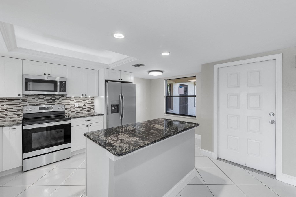 a kitchen with white cabinets and a marble counter top