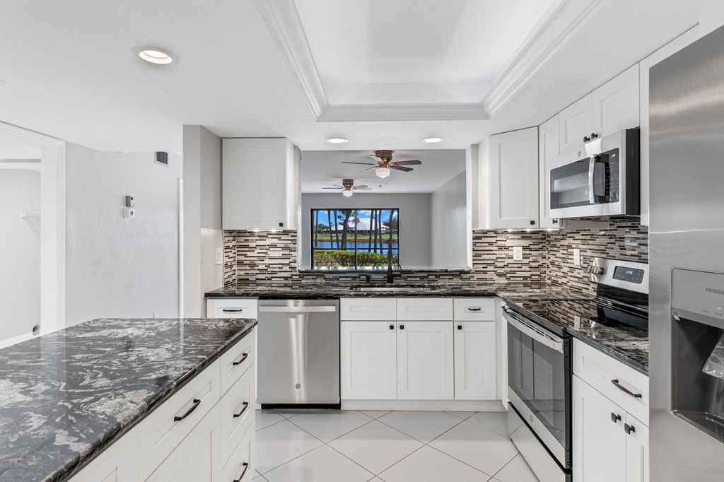 the kitchen has granite counter tops and white cabinets