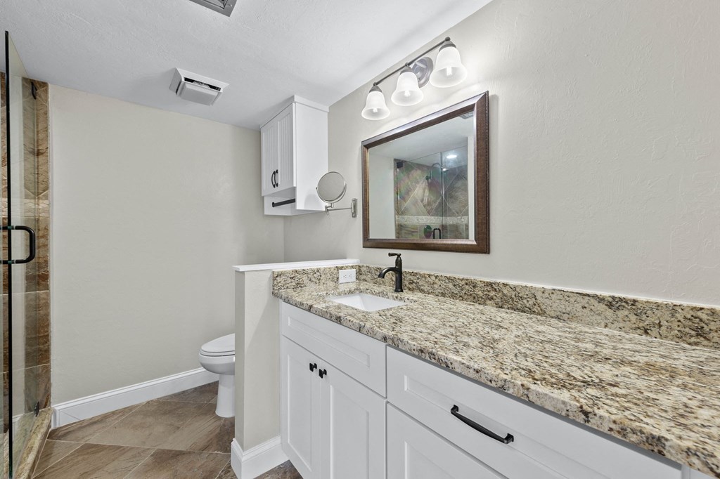 a bathroom with white cabinets and a granite counter top