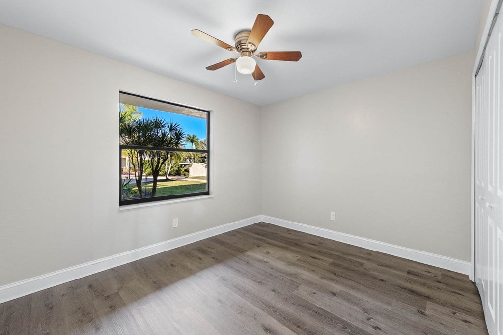 an empty living room with a ceiling fan and a window