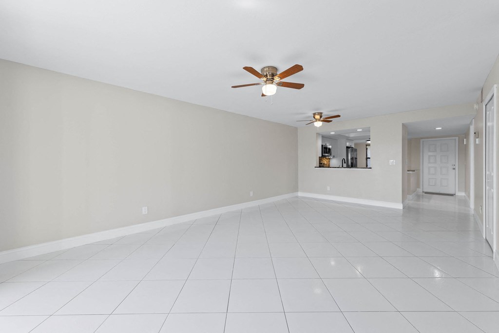 an empty living room with a ceiling fan and a white tiled floor