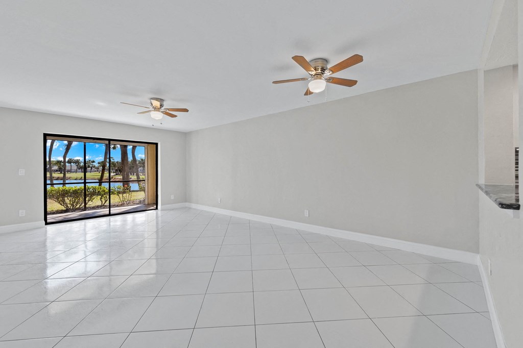 an empty living room with two ceiling fans and a sliding glass door