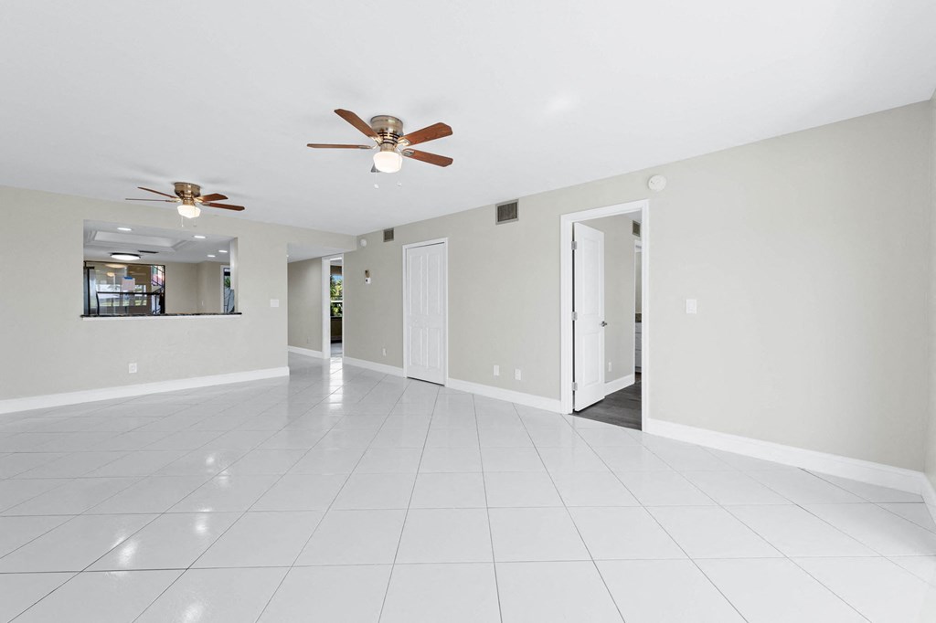 the spacious living room with white tile flooring and ceiling fans