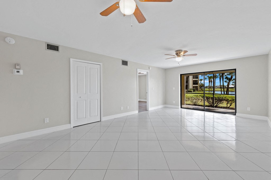 the living room has a large white tile floor and a door to the balcony