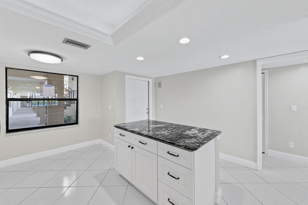 a white kitchen with white cabinets and a marble counter top