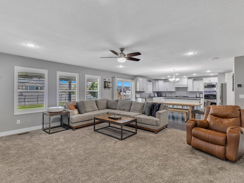 a living room with couches and chairs and a ceiling fan