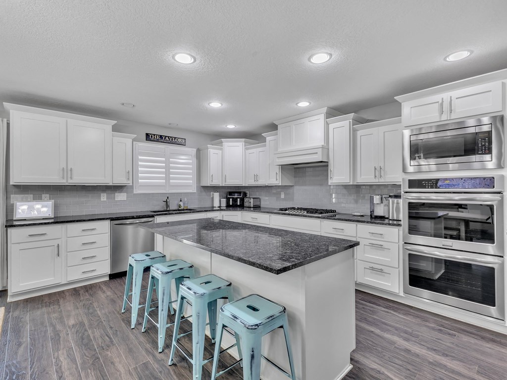 a kitchen with white cabinets and a large island with blue stools