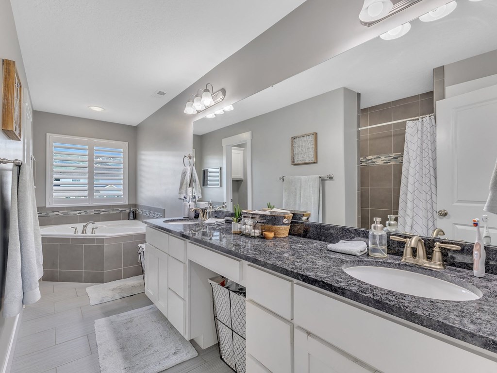 a white and gray bathroom with two sinks and a tub
