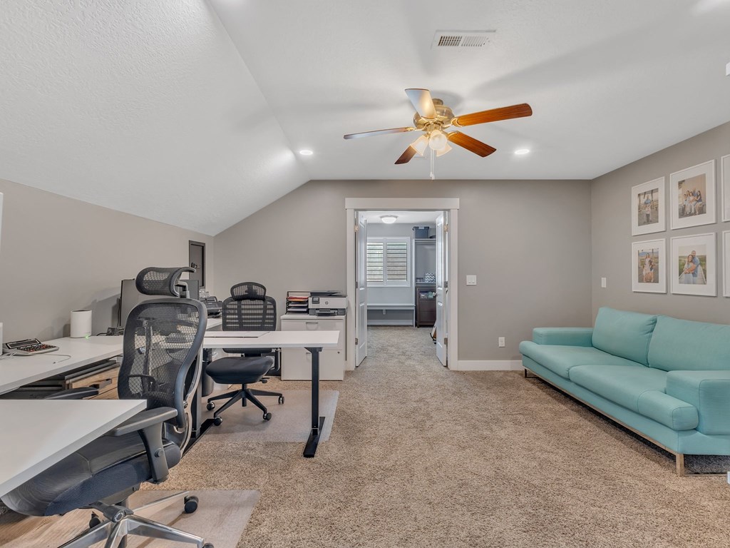 a home office with two desks and a ceiling fan