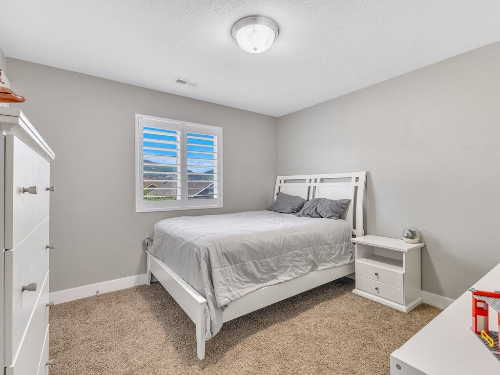 a white bedroom with a white bed and a window