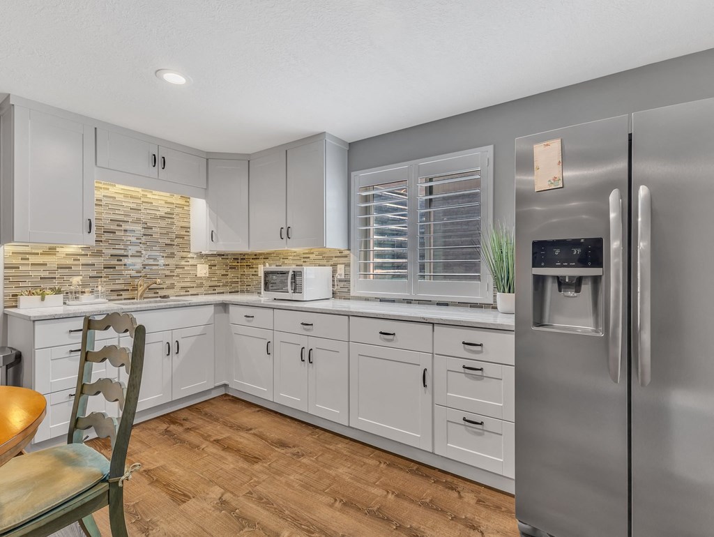 a kitchen with white cabinets and a stainless steel refrigerator