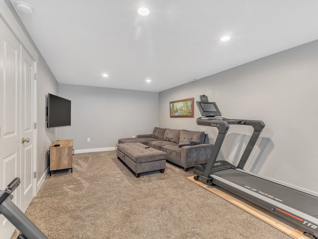 a living room with a treadmill and a couch and a tv