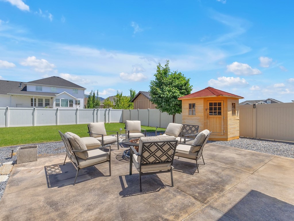 a backyard patio with a table and chairs and a small house