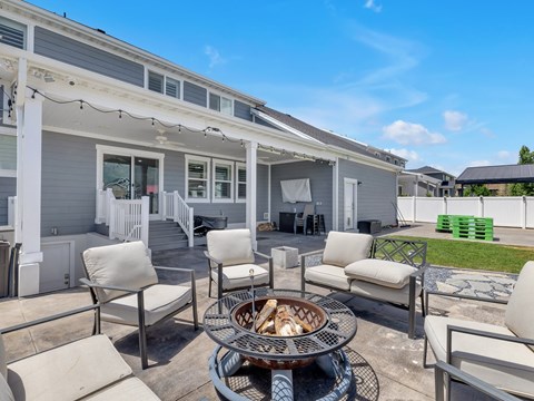a patio with a fire pit and chairs and a house