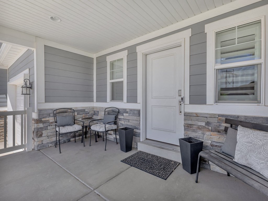 the front porch of a house with a porch swing and two chairs