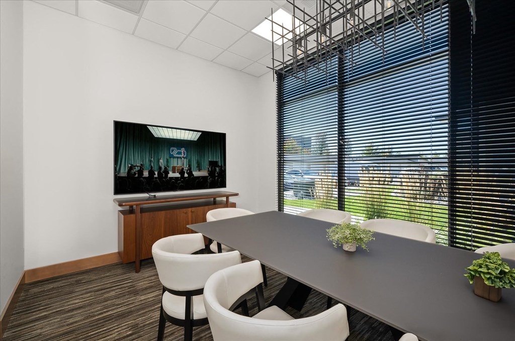 a conference room with a table and chairs and a television