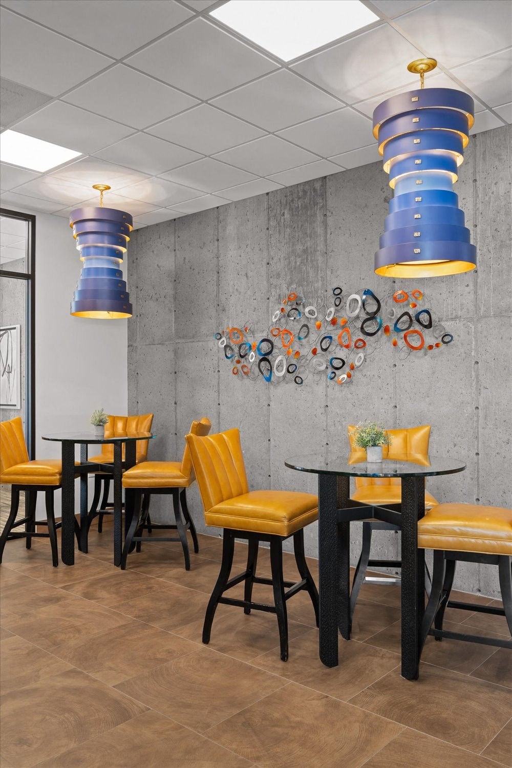 a dining room with yellow and blue chairs and tables