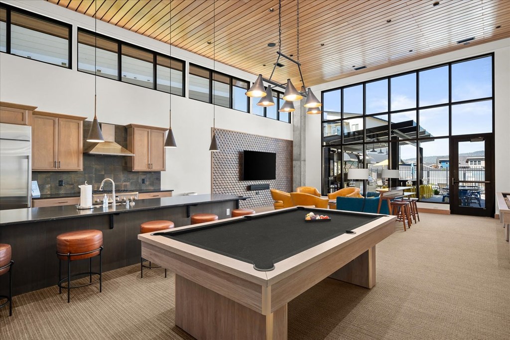 a pool table in a clubhouse with a kitchen and living room