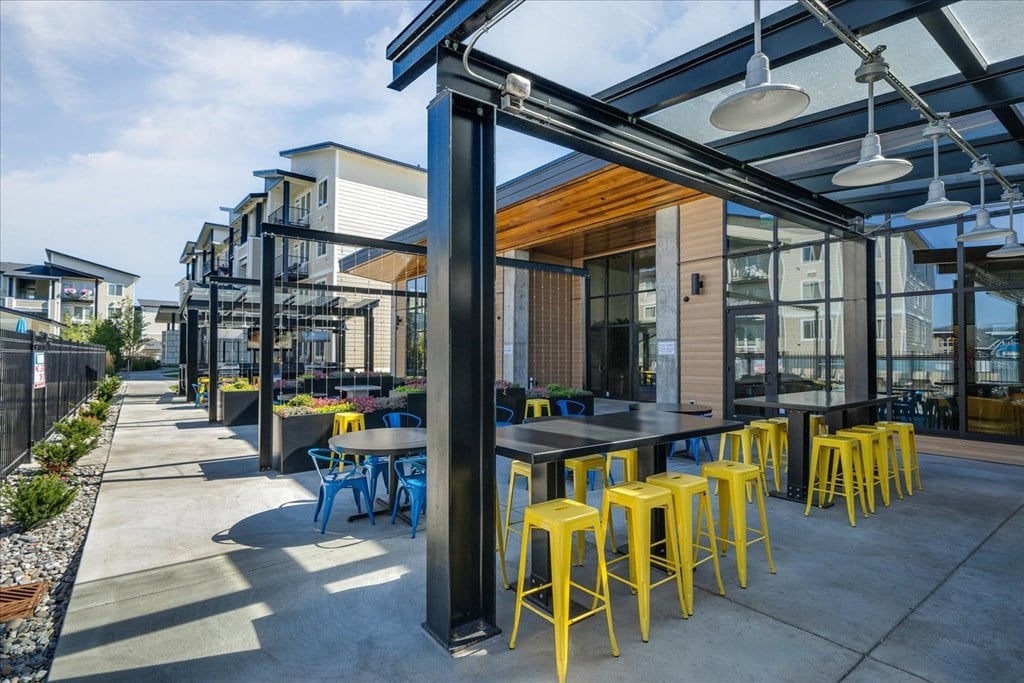 a patio with yellow stools and tables and glass ceilings
