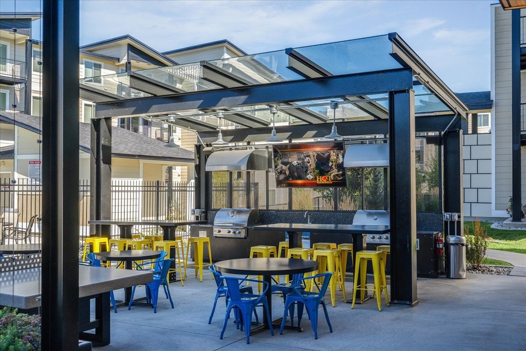 a patio with tables and chairs and a grill