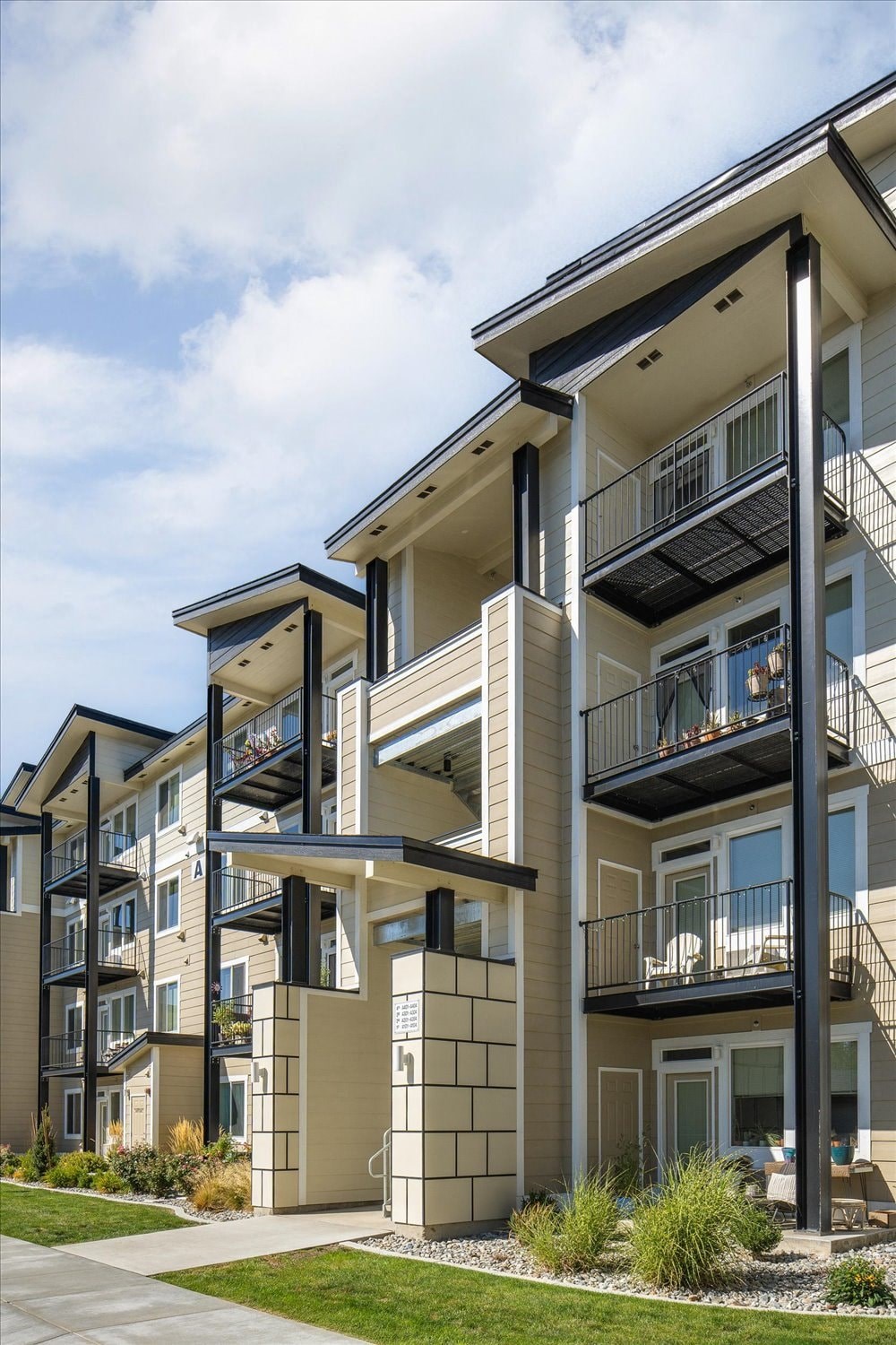 a row of modern apartments with balconies and grass