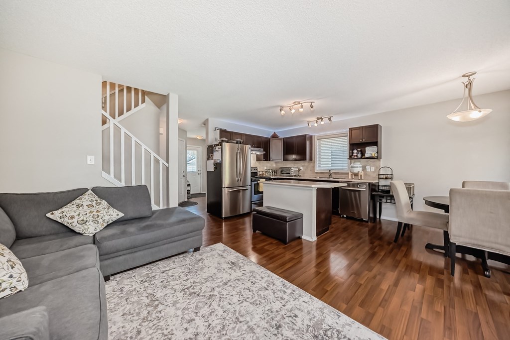 a living room with a couch and a kitchen with a staircase