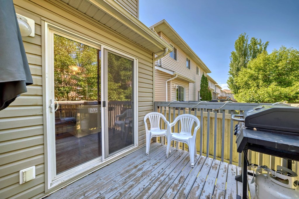 a patio with two chairs and a grill on a deck