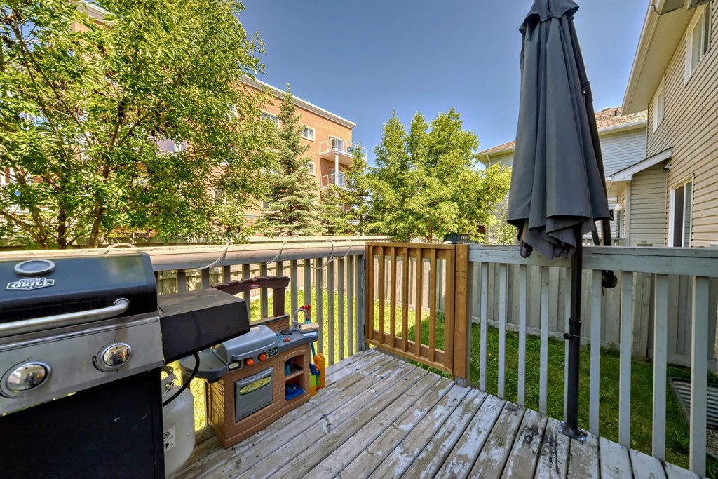 a backyard deck with a grill and an umbrella