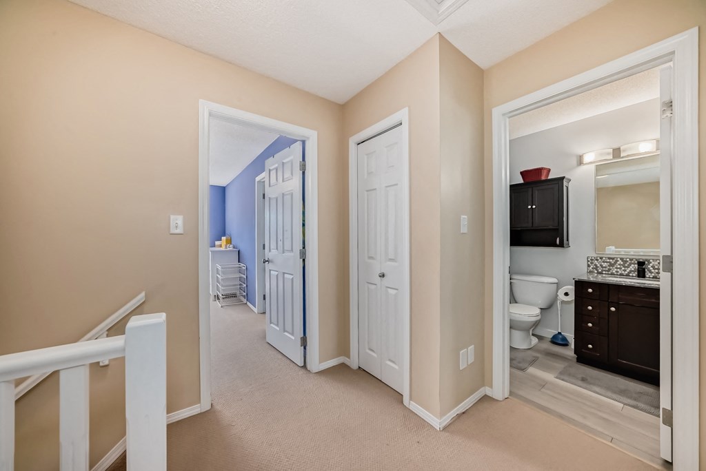 a hallway with a door to a bathroom and a door into a bedroom
