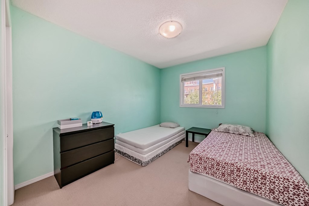 a bedroom with two beds and a dresser and a window