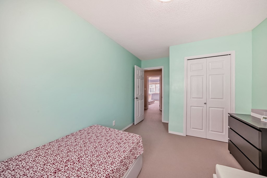 a bedroom with a bed and a closet and a door to a hallway