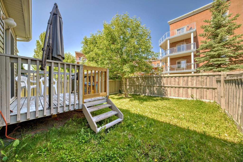 a backyard with a wooden fence and a deck with a swing