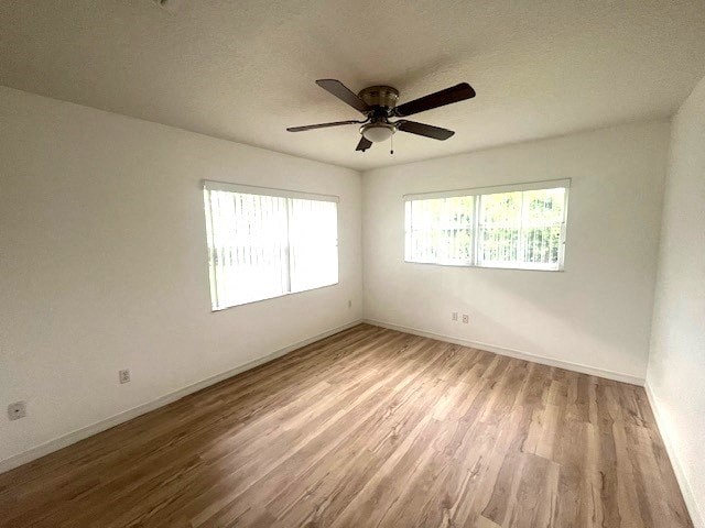 an empty living room with a ceiling fan and wood floors